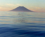 Photograph of a volcanic island arising from a calm sea